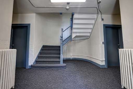 A staircase with a metal railing and steps leading up to a door.