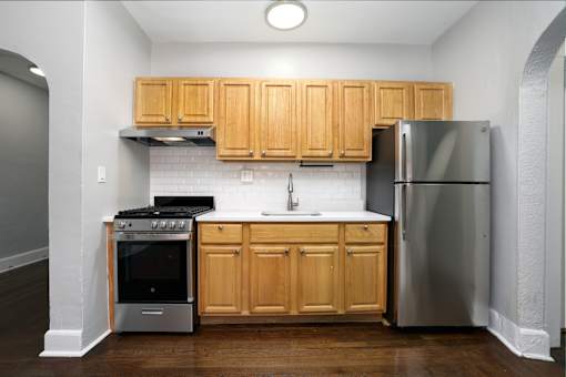 A kitchen with wooden cabinets and a stainless steel refrigerator.