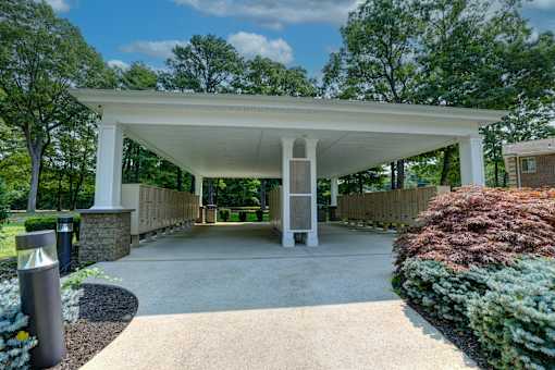 A white pavilion with a stone pillar and a concrete floor.