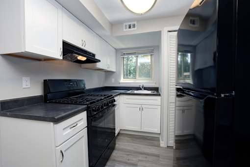 A kitchen with black appliances and white cabinets.