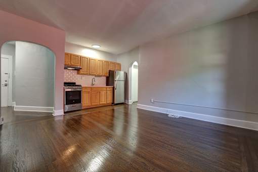 A kitchen with wooden floors and a pink wall.