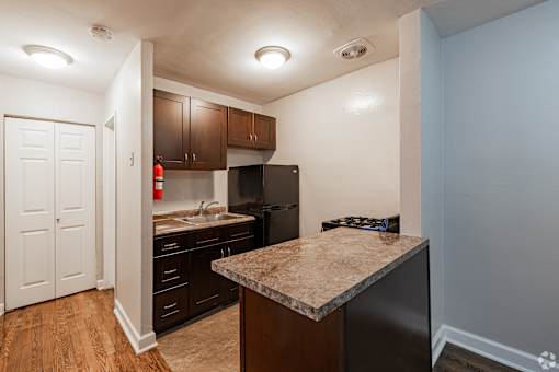 A kitchen with a granite countertop and wooden cabinets.