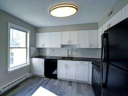 A kitchen with black appliances and white cabinets.