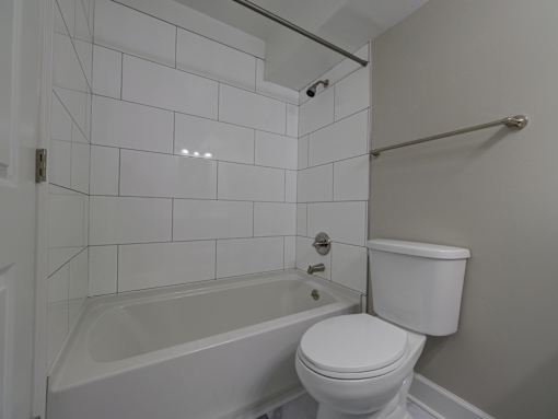 A white toilet sits next to a bathtub in a bathroom.