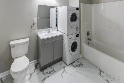 a white bathroom with a washing machine and a toilet and a sink