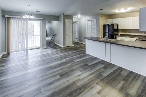 a kitchen and living room with wood flooring in an apartment