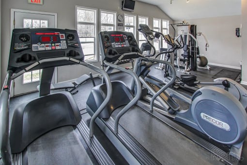 a gym with cardio equipment and windows in a home gym