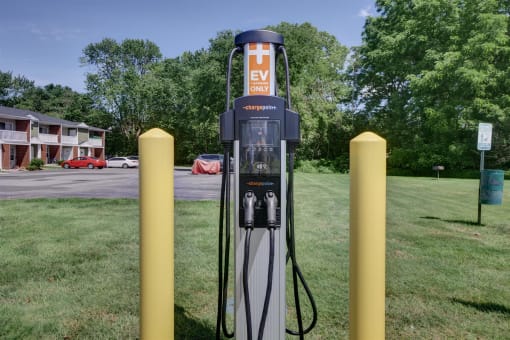 a gas pump sitting in the grass next to some yellow poles
