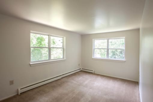 a small bedroom with two windows and a carpeted floor