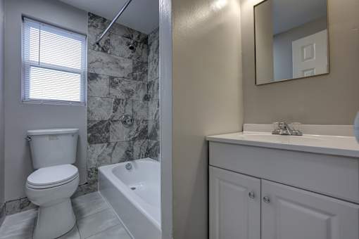 A white toilet sits next to a white bathtub in a bathroom.