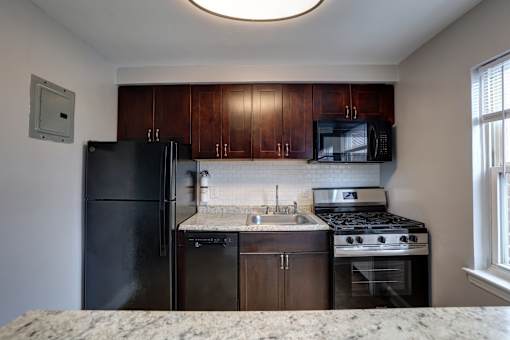 A kitchen with black appliances and brown cabinets.