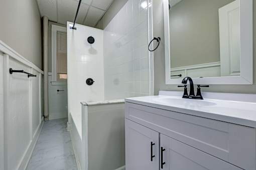 A white bathroom with a white sink and a white cabinet.