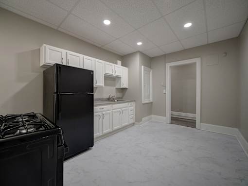 A kitchen with a black refrigerator and a black stove top at Willett Apartments, Albany, New York