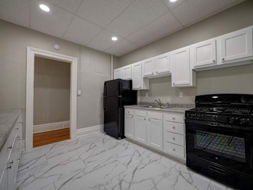 A kitchen with black appliances and white cabinets at Willett Apartments, Albany, New York