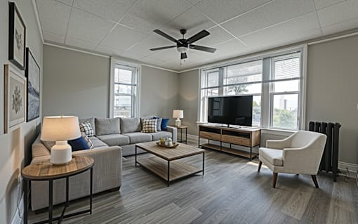 A living room with a grey couch, a coffee table, a television, and a chair.