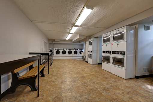 A kitchen with a table and benches and ovens.