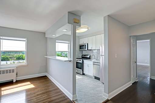 A kitchen with white cabinets and a window overlooking a green landscape.
