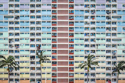 A tall building with a red stripe in the middle and palm trees in front.