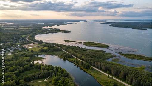 An aerial view of a river flowing through a forested area with a cloudy sky above.