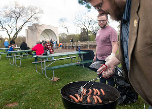 a group of men grilling hot dogs on a grill
