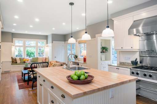 A modern kitchen with a wooden island and pendant lights.
