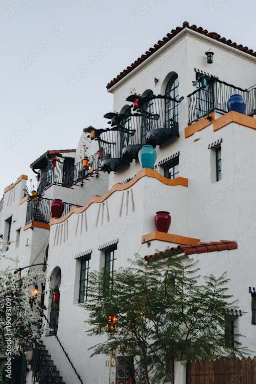 A white building with balconies and plants.