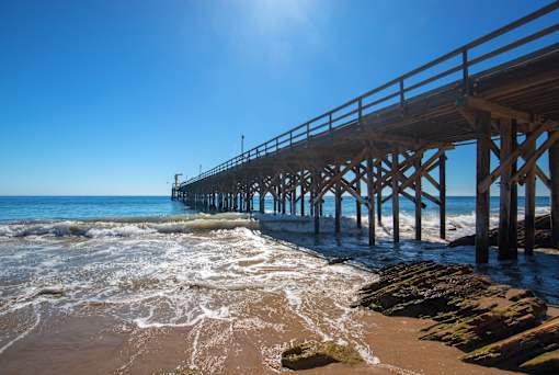 A pier extends into the ocean under a clear blue sky.