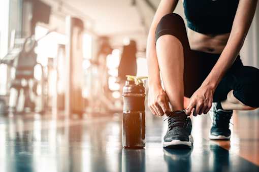 A person tying their shoelaces in a gym.