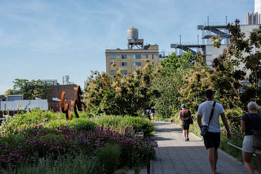People walking on a path in a park with a water tower in the background.