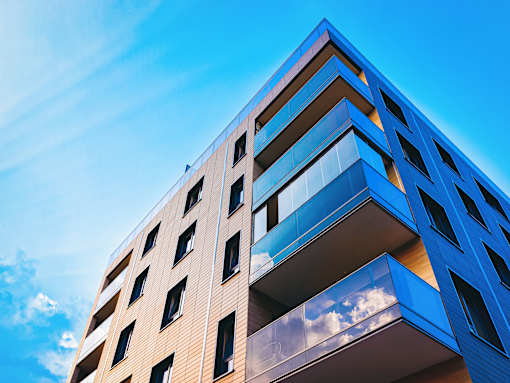 A modern building with balconies and a blue sky in the background.