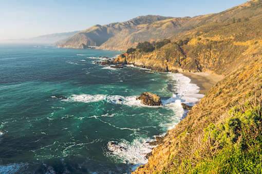 A coastal landscape with waves crashing against the shore.