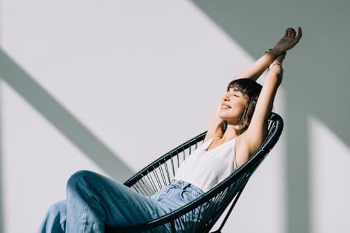 A woman is sitting in a chair with her arms raised.