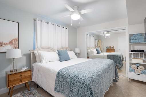 A bedroom with a bed, nightstand, and a ceiling fan.