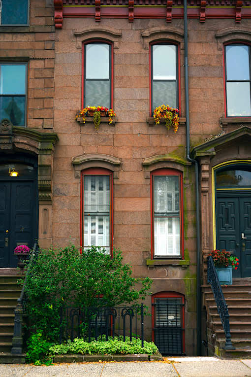 A brown building with a black door and windows with flower boxes.