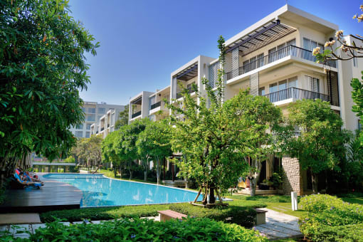a large swimming pool in front of a building with trees