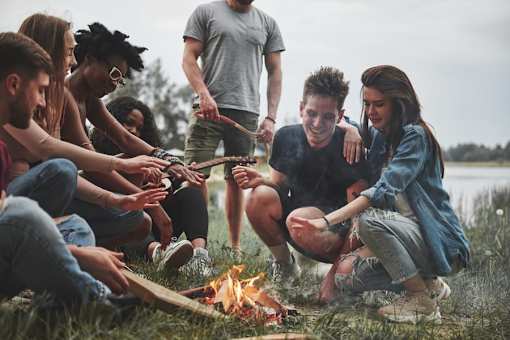 a group of people sitting around a campfire playing with a rope