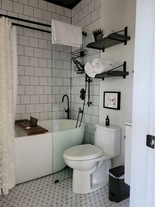 A white toilet sits under a white shower curtain in a bathroom.