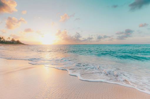 A serene beach scene with the sun setting over the ocean.