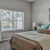 A bed with a brown comforter sits in a room with a window.