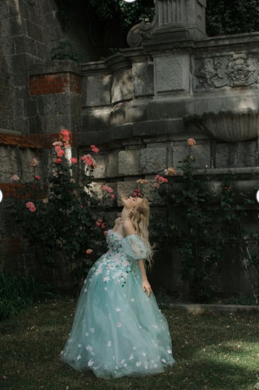 a girl in a blue dress looking up at flowers