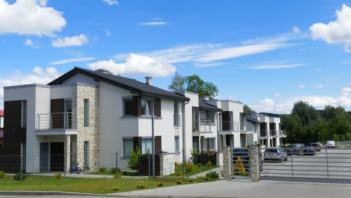 a row of houses with a parking lot in the foreground and a blue sky in the background