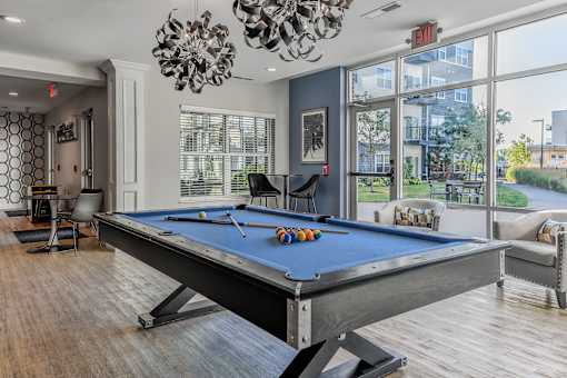 a pool table in a living room with a large window
