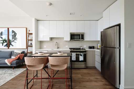 a kitchen with white cabinets and a counter with two chairs