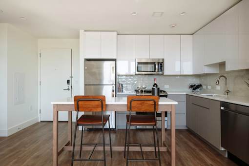 a kitchen with white cabinets and a table with three chairs