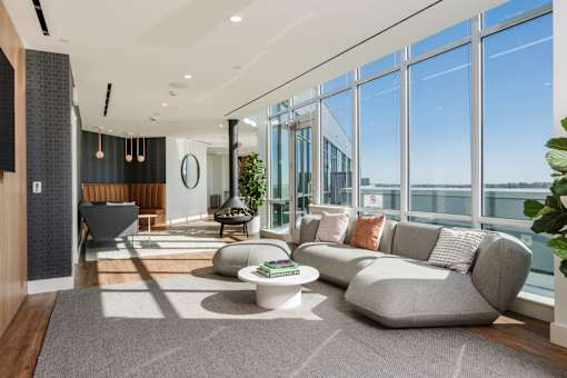 a living room with a couch and a table in front of glass walls