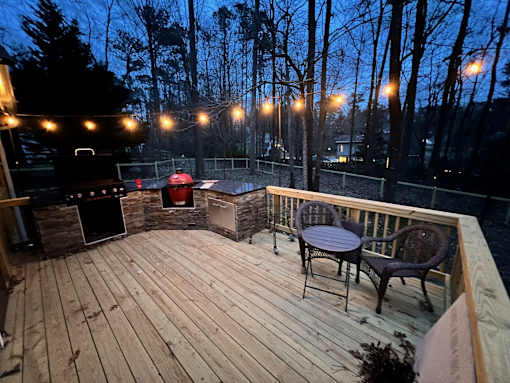 the deck is lit up at night with a grill and lights