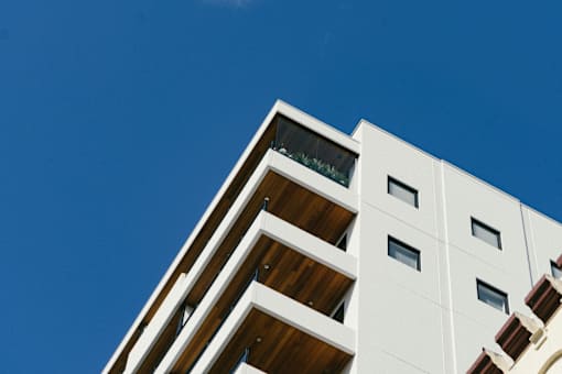 A white building with balconies and windows against a blue sky.