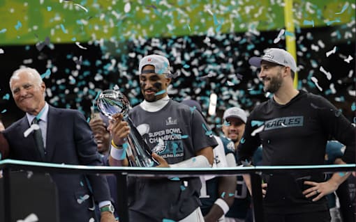 Three men celebrate with a trophy and confetti in the air.