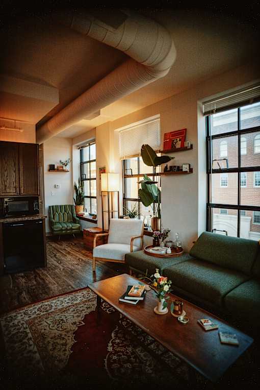 A living room with a green couch, a wooden coffee table, and a large window.
