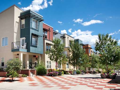 A modern building with a green and white facade is surrounded by a courtyard with a red and white checkered floor.